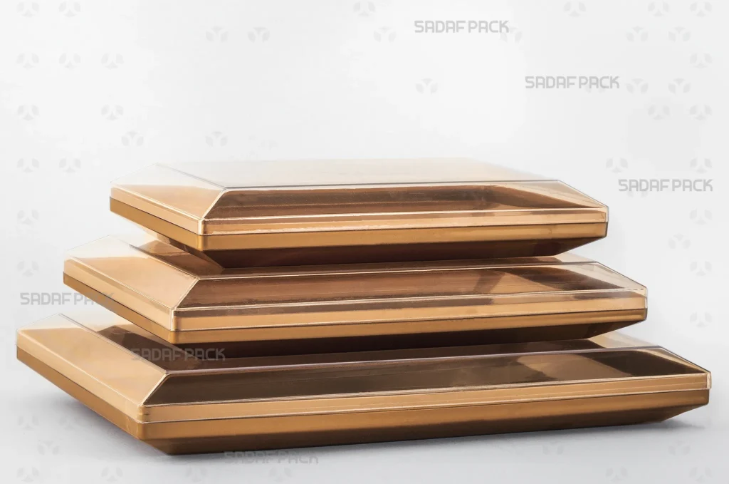 مجموعه ظروف مستطیلی طلایی در سایزهای 200،300 و 500 از برند صدف پک که برای کاربردهای متنوع بسته‌بندی شیرینی و خشکبار چیده شده‌اند. 