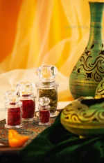 مجموعه ظروف کریستالی سری میلاد صدف پک در سایزهای مختلف، حاوی زعفران صادراتی و هل سبز که بر روی پارچه ترمه جهت نمایش چیده شده‌اند.